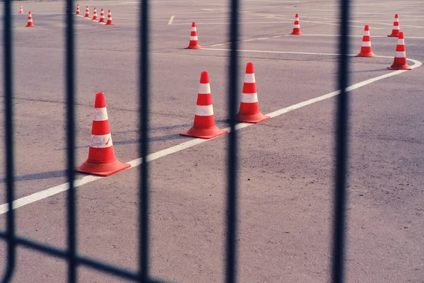 A quarantined coronavirus area for driving instruction. A fence with a grid and a school for training drivers with cones