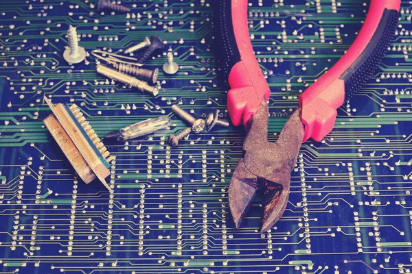 Pliers for electronics repair against circuit board