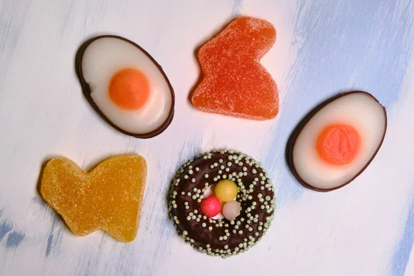 Candy for Easter in the form of a rabbit made of marmalade and chocolate eggs on a white background