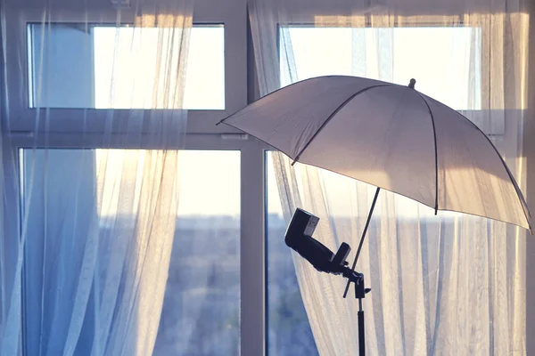 Umbrella and flash for the camera on the background of the home window