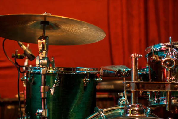 Green drum set on red background. Percussion instruments at a jazz concert. Drum and plates are on the stage of the concert hall