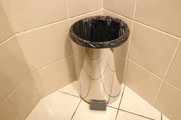 Metal trash can without cover with the package. Garbage collection in the bathroom at home or in the office. Open trash can in the toilet.