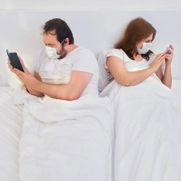 Man and woman look at the phones with their backs turned. Family relationships in isolation due to coronavirus.