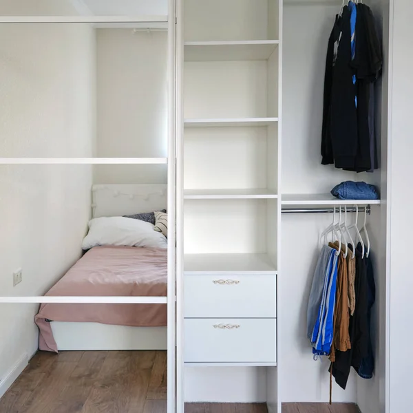 Wardrobe with mirror doors and clothing in the bedroom