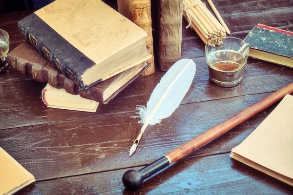 Books, paper and feather for writing in ink. Table with retro writing utensils.