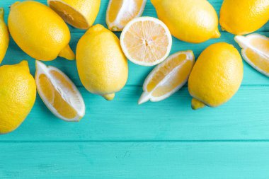 Turkuaz ahşap arka planda yaprakları olan taze kesilmiş limonlar. Alt kopya alanı ile yukarıdan görüntüle.
