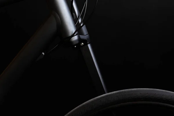 Close up photo of the black bike frame,  lefty fork and wheel on the black background