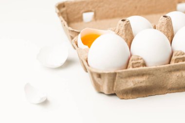 Beyaz arka planda beyaz yumurtalı makro shot. Bir yumurta kırılır ve yumurta sarısı beyaza açılır. Beyaz kabuk etrafta yatıyor..