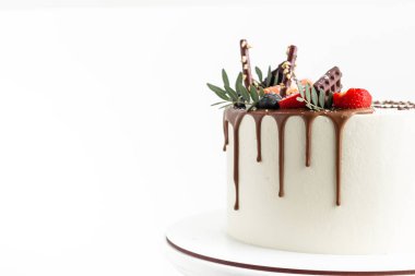Çikolatalı düğün pastası, kırmızı böğürtlenlerle süslenmiş çikolata ve beyaz arka planda fotokopi alanı ile fıstıklı.