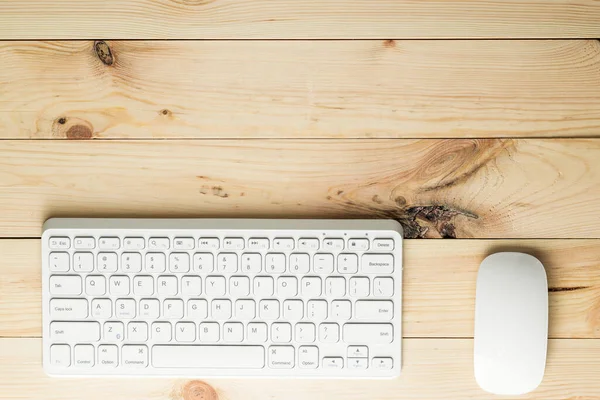 top view of workspace with white computer keyboard and mouse on the wooden table with space for text