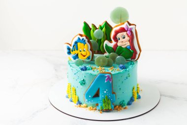 Kyiv, Ukrayna - 12 Ekim 2020: Disney Prensesi Ariel ve arkadaşı Flounder balık kurabiyeleri doğum günü pastasının üstünde. Deniz konseptli turkuaz kek.
