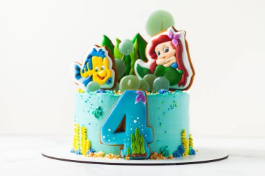 Kyiv, Ukrayna - 12 Ekim 2020: Disney Prensesi Ariel ve arkadaşı Flounder balık kurabiyeleri doğum günü pastasının üstünde. Deniz konseptli turkuaz kek.