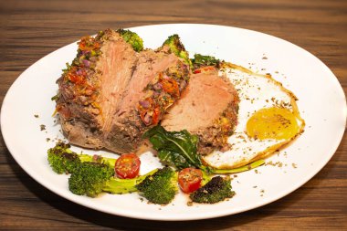 Kızarmış ve baharatlı et ve yanında kızarmış yumurta, brokoli, soğan ve domates..