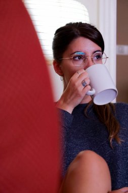 Genç bir kadın sabah kahvesini evinde içiyor. 