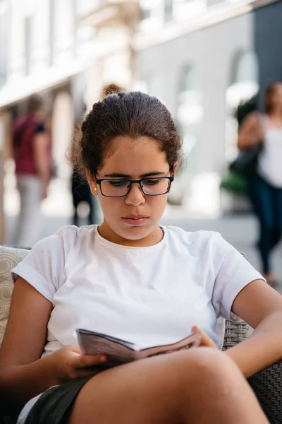 Sokakta oturan okuma kız gözlük — Stok fotoğraf