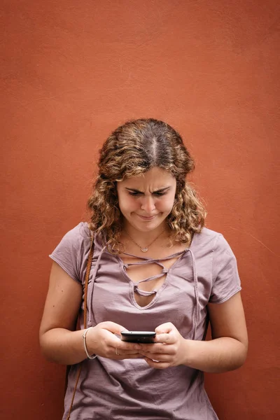 Beautiful young woman with weird face texting on her smart phone