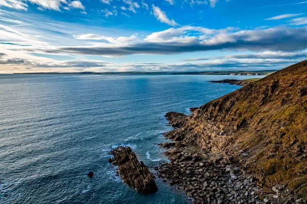 Vista panorâmica de falésias na costa irlandesa com colinas verdes ao pôr-do-sol . — Fotografia de Stock