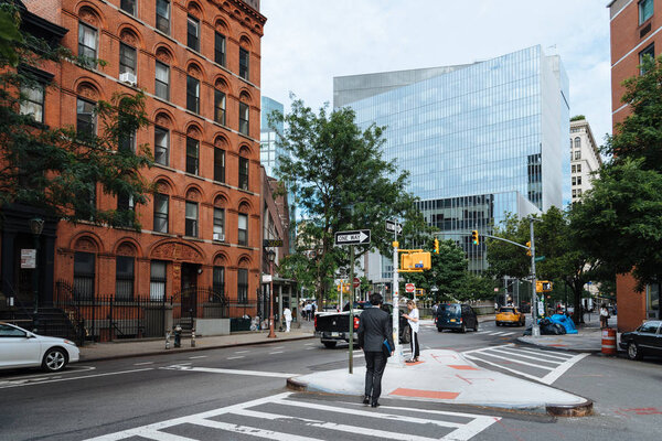 Вид сзади на человека, переходящего улицу Стайвесант в Восточном Нью-Йоркмане
