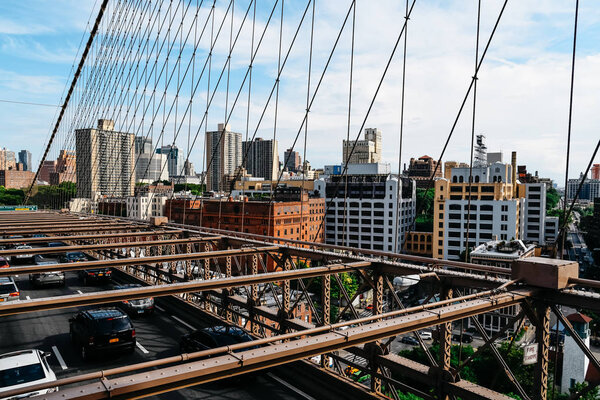 New York City, USA - June 20, 2018: Cars speeding on Brooklyn Bridge, Manhattan against skyline. It is one of the most iconic bridges in the world