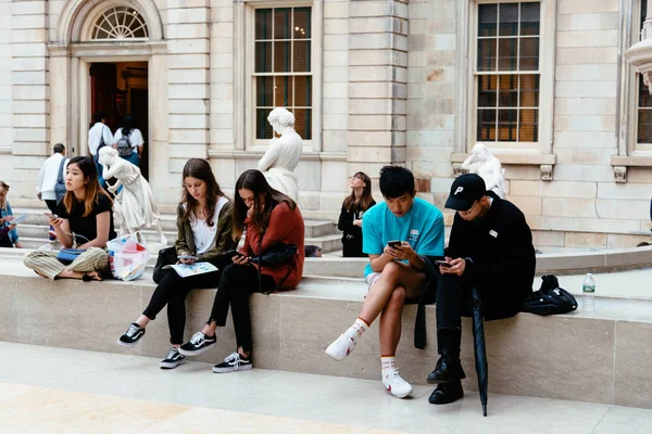 Cep telefonları ile müze üzerinde oturan genç insanlar — Stok fotoğraf