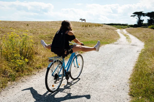 Hübsche junge Frau mit Fahrrad auf einer Landstraße — Stockfoto