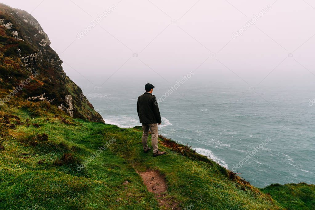 Man wearing cap stands alone in the cliffs