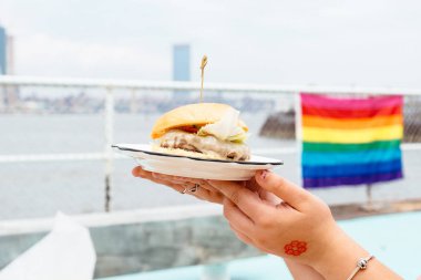 Burger gökkuşağı bayrağı ile arka planda tutan kadın