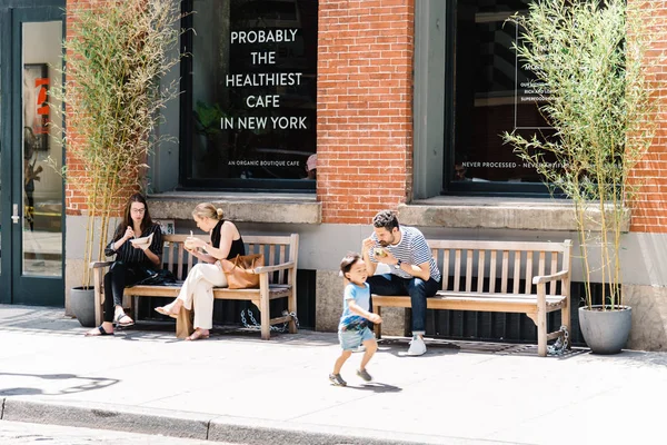 Emberek ülnek a padokon élvezi ebéd, a New York-i SoHo-ban — Stock Fotó