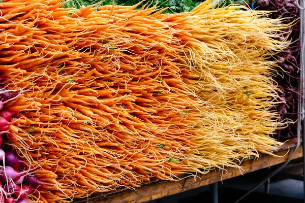 橙色小胡萝卜和萝卜堆在市场上 — 图库照片