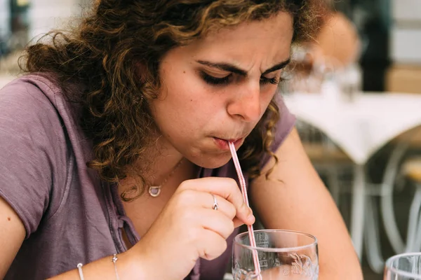 Young woman concentrated drinking soda with straw — Stock Photo, Image