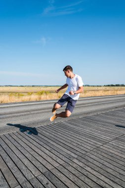 Genç adam manzara karşı tahta üzerinde atlama