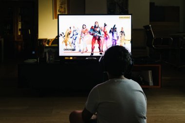Teenager playing Fortnite video game with PlayStation on TV clipart