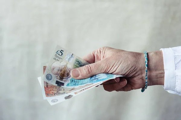 Woman holding pounds sterlings against background — 스톡 사진