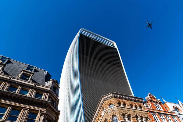 Londra'da gökdelenin üzerinde gökyüzüne uçan uçak — Stok fotoğraf