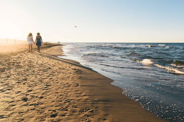 Persone che camminano sulla spiaggia al tramonto — Foto Stock