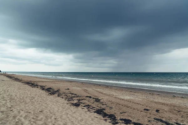 Strand met donkere wolken en inkomende regen storm — Stockfoto