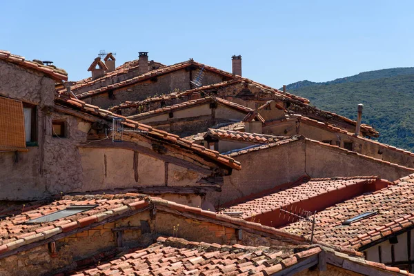 Háttér a régi falusi házak kő falak és vörös cserép tetők — Stock Fotó