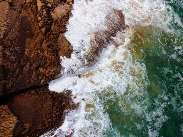 Vue aérienne du dessus des vagues de mer frappant des rochers sur les falaises — Photo