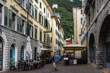 Riva del Garda, İtalya - 20 Ağustos 2025: Riva del Garda, İtalya 'da tarihi mimari ve günün tadını çıkaran insanların yer aldığı hareketli bir kasaba meydanı.