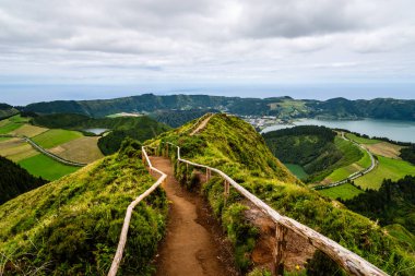 Volkanik bir tepenin üzerindeki manzaralı yürüyüş yolu Sao Miguel, Azores 'deki göllerin ve kıyı şeridinin çarpıcı panoramik manzarasını sunuyor.