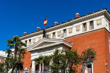 Madrid, İspanya - 01 Nisan 2024: İspanya Kraliyet Akademisi Madrid 'de İspanyol bayrağı, neoklasik cephe ve mavi gökyüzü dalgalanan binası