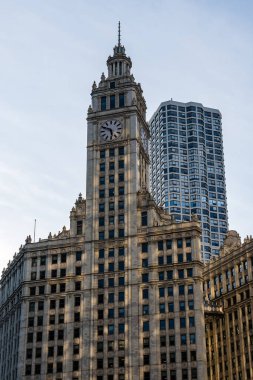 Resim, Chicago 'nun mimari kontrastını, klasik bir saat kulesinin detaylı bir görüntüsünü ve temiz bir gökdelene karşı modern bir gökdeleni gösteriyor..