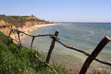 Ev yapımı çitleri olan güzel bir manzara ve ön planda yeşil çimenler ve arka planda deniz.