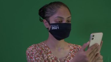 2021 'de Yüzü Maskeli Genç Asyalı Kadın Akıllı Telefonu Tutuyor. Yeşil Ekran, Kilitli