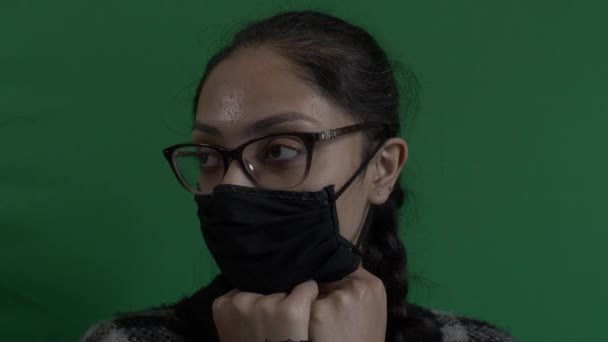Ung Kvinna Bär Ansiktsmask Med Händerna Vilande Hakan Ser Rätt — Stockvideo
