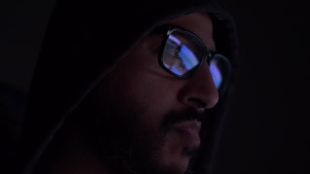 暗い部屋でメガネで見られるコンピュータ画面の反射とフード付きアジアの男性 ロックオフ サイドビュー — ストック動画