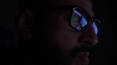 Geceleri bilgisayar ekranına bakan gözlüklü Asyalı bir erkek. Kilitli