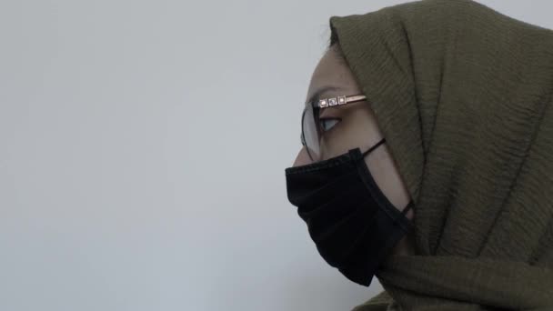 黒の綿の顔マスクを身に着けているメガネを持つヒジャブ女性 ロックオフ 左側のビュー — ストック動画