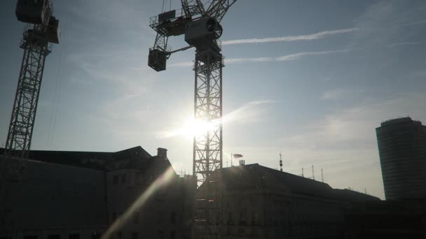 ロンドンのウェストミンスターで青い空に太陽が昇る2つのクレーンのシルエット ロックオフ — ストック動画