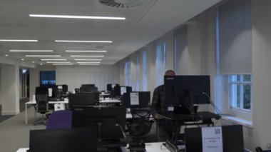 Yetişkin İngiliz Asyalı erkek, boş bir ofiste çalışıyor ve tecrit sırasında çekip gidiyor. Kilitli 